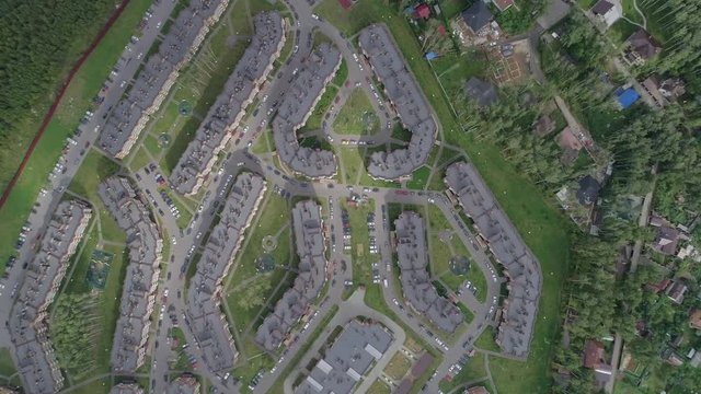 Shooting a residential area with low-rise buildings, roads on which cars go, aerial photography, the camera moves away from the object on a summer day
