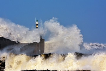 Fototapeta na wymiar Stormy wave over lighthouse of San Esteban de Pravia.