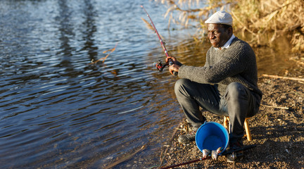 Positive fisherman sitting near river