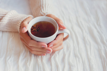 Women holds a cup of hot tea with anise star. Cozy morning at home.