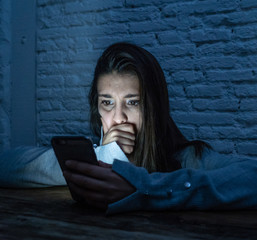 Close up portrait of a woman with her smart phone in the dark suffering Internet cyberbullying