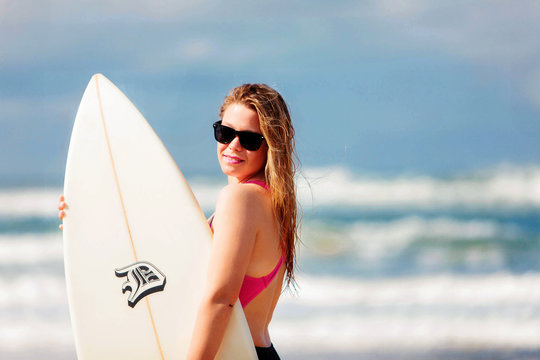 A very happy blonde woman on the beach in her bikini is smiling