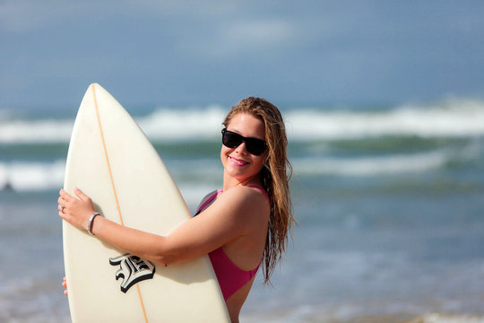 A very happy blonde woman on the beach in her bikini is smiling