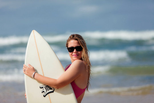 A very happy blonde woman on the beach in her bikini is smiling
