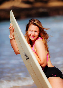 A very happy blonde woman on the beach in her bikini is smiling