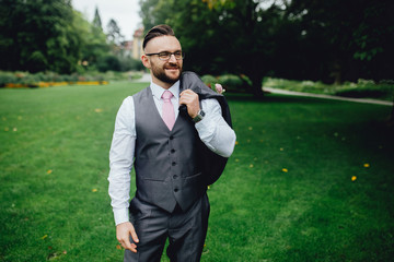 Portrait of a handsome groom in a grey suit with a tie and vest.