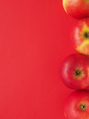 Red organic apples on a red background