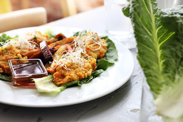 Colorful baked french fries with vegetables served with vegetable stew on iceberg lettuce.