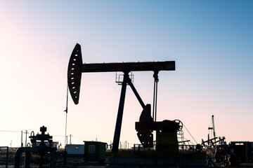 Oil pumps are running in the sunset at the oil field.