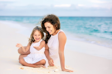 Mother with little daughter playing on ocean beach, Maldives