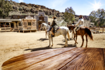 Wooden old table of free space for your product. Blurred background of Wild West city in America. 
