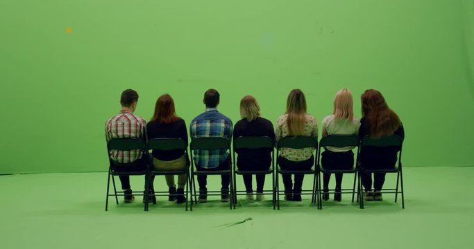 GREEN SCREEN CHROMA KEY Back view group of young people sitting on chairs. 4K UHD ProRes 4444