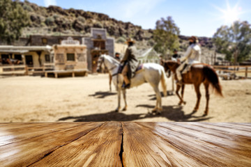 Wooden old table of free space for your product. Blurred background of Wild West city in America. 