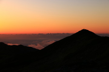 Obraz premium 東北飯豊連峰 飯豊山頂直下 本山小屋から 夕焼けと飯豊山山頂シルエット