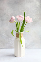 Pink tulips in vase on grey background