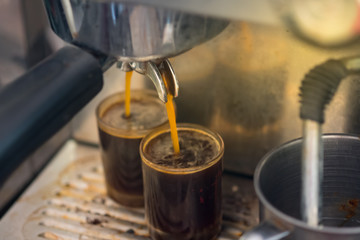 Close up of espresso pouring from coffee machine to shot glass.