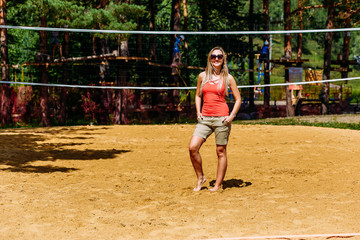 sporting a smiling tanned woman in sunglasses is standing on the yellow sand on the beach