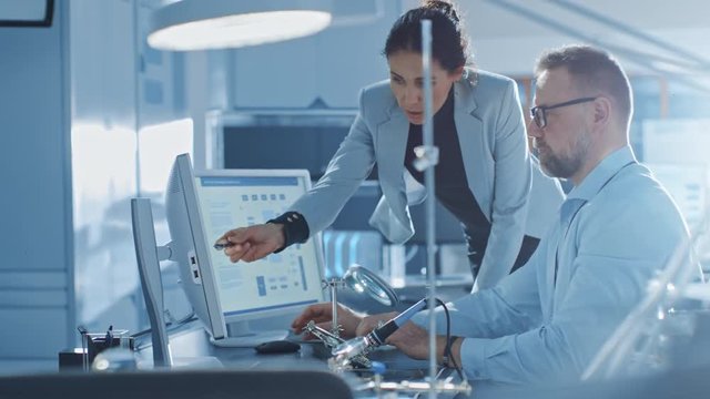 Female Chief Engineer Talks with Male Electronics Specialist, Explaining Things, He Works on Computer and Agrees with Her. Modern and Bright Office with Stylish People 