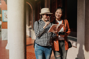 two happy cheerful smiling asian girl travelers walking in corridor at Confucian temple. young...