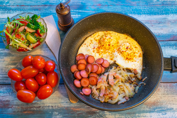 Scrambled eggs with bacon, onion and sausage.