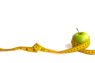 Green apple and measuring tape with centimeters and inches isolated on white background.