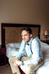 A man sits on the edge of the bed and waits