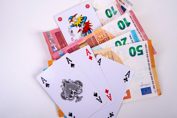 four playing cards with joker and asses with euro banknotes game winnings