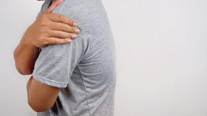 Side view of man has shoulder ache or upper arm pain with blurred white wall background, health care and problems concept