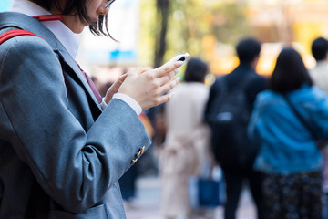 スマホを操作する制服の女子高生