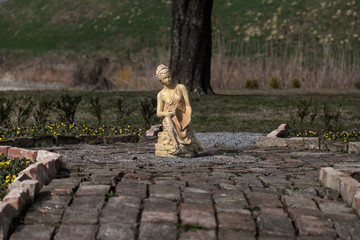 Fototapeta premium Woman statue in a garden illuminated with afternoon light