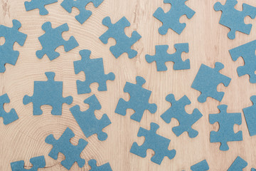 top view of blue puzzle pieces scattered on wooden table