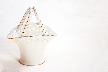White porcelain basket with handles with gold interlacing on a white background, closeup. Decorative white vase with gold rim, with copy space for text. Gift idea, empty basket, porcelain tableware.