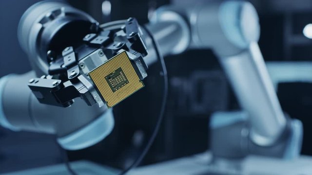 Modern High Tech Authentic Robot Arm Holding Contemporary Super Computer Processor Smoothly Moving into Focus. Industrial Robotic Manipulator End Effector Holding CPU Chip Moves Towards Camera Focus