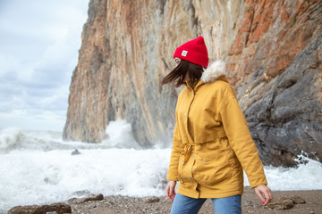 Girl on the sea on the background of the rocks. High waves beat on the rock.