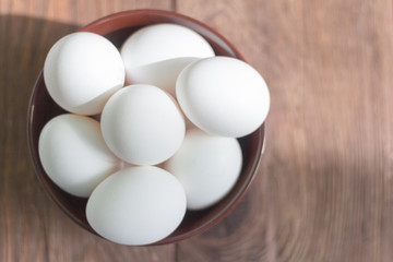 white chicken eggs in bowl on wooden background