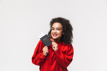 Naklejka premium Smiling african woman in red sweater holding passport with tickets