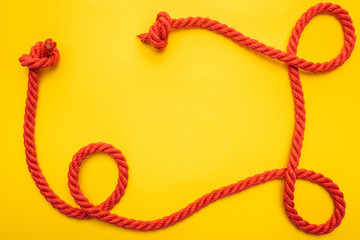 curled and red rope with twisted knots isolated on orange