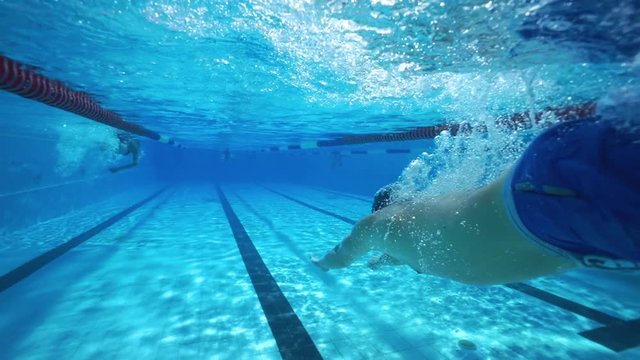 Strong athletic man swimming underwater in clear spa pool