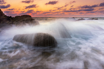 Beautiful natural seascape wave moving on the rock during sunrise