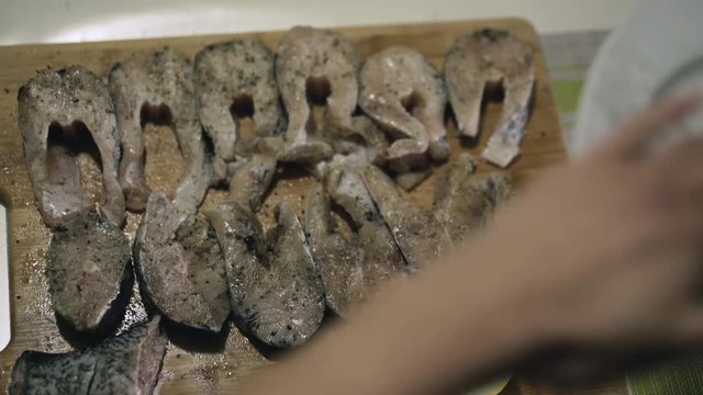 Female hands marinating and strewing spices on fish fillet on wooden tablet. 4K