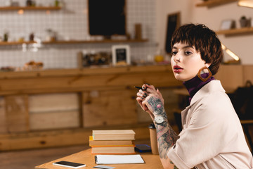 confident businesswoman sitting at table in cafe and looking away