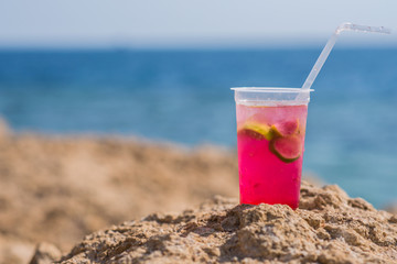 Bright cocktail placed on a sunny summer beach against the blue sea - Image