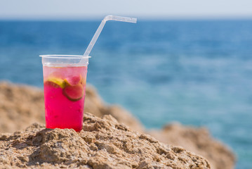Bright cocktail placed on a sunny summer beach against the blue sea - Image