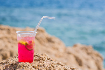 Bright cocktail placed on a sunny summer beach against the blue sea - Image