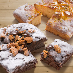 two square cakes cutted on wooden table, jam and chocolate flavor