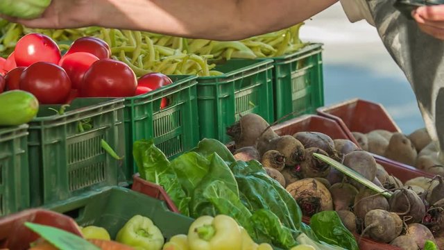A lady is buying some food products at a local market this morning. She picks one of the items and puts it into her bag.