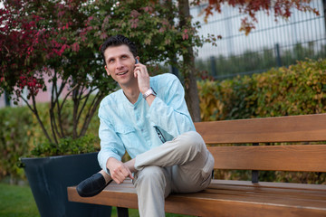 Fototapeta premium Handsome man talking on his mobile phone in a park