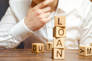 Wooden blocks with the word loan and businessman. Consumer, banking and property loan. Business and entrepreneurial development. Small business loans. Interest rate repayment. Planning