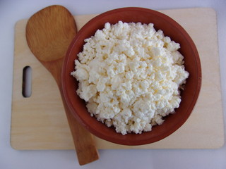 cottage cheese in a clay pot with a spatula