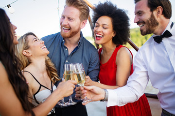 Group of happy friends partying and toasting drinks